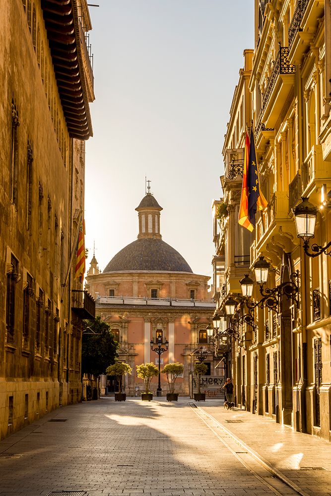 Narrow cobblestone street and Cathedral Dome near Placa de la Mare de Deu, Valencia, Spain.